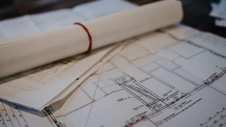 Zusammengerollte Pläne liegen aufm Tisch